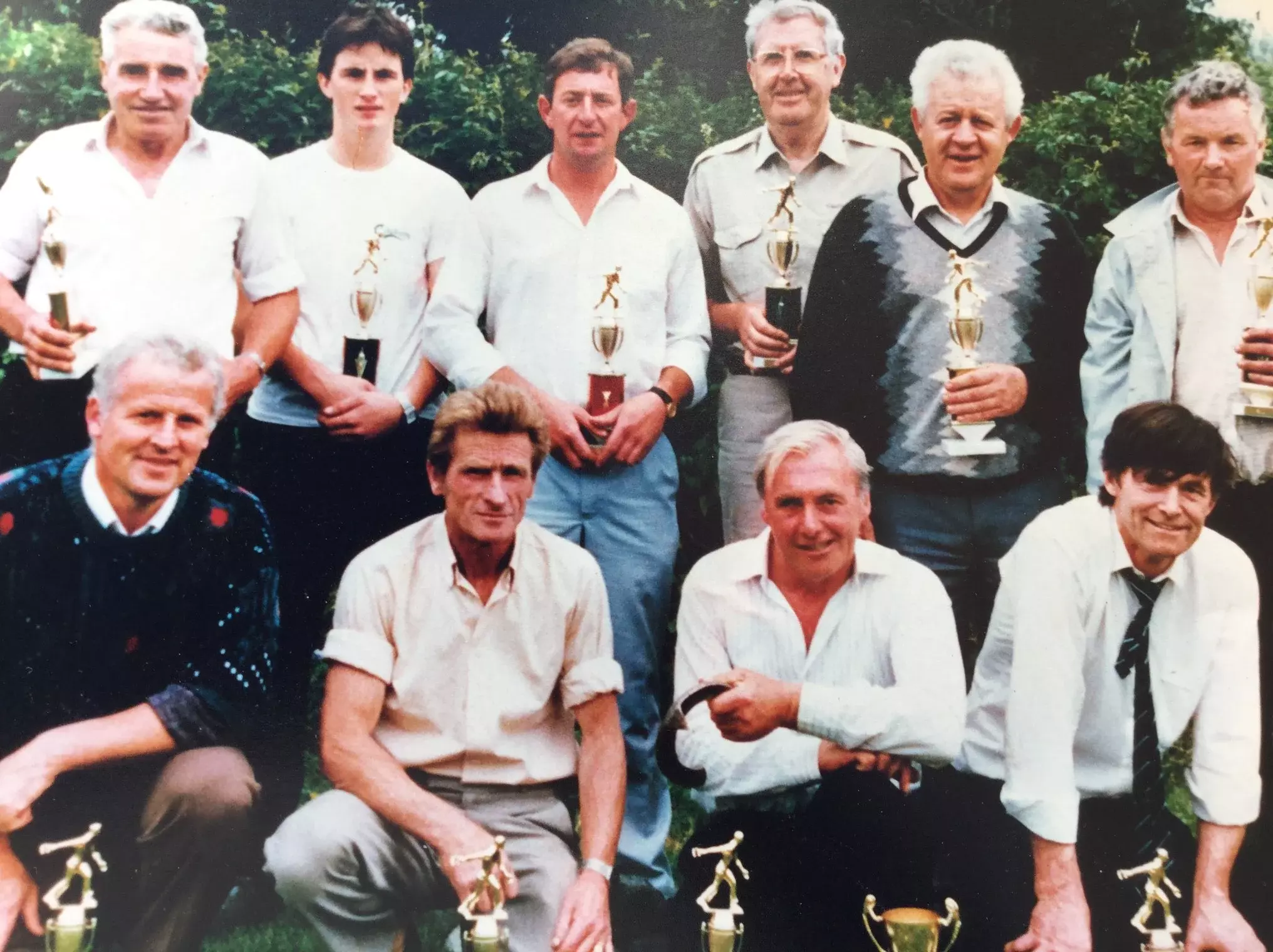 Ten men holding trophies as a team.